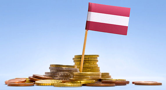 Das Symbolfoto zeigt einen Stapel Euromünzen und die österreichische Flagge.