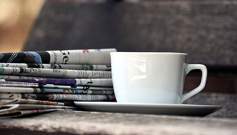 Kaffeetasse mit Zeitungsstapel