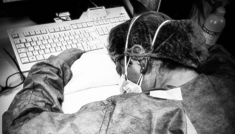 Foto einer erschöpften Ärztin, die auf der Computertastatur schläft