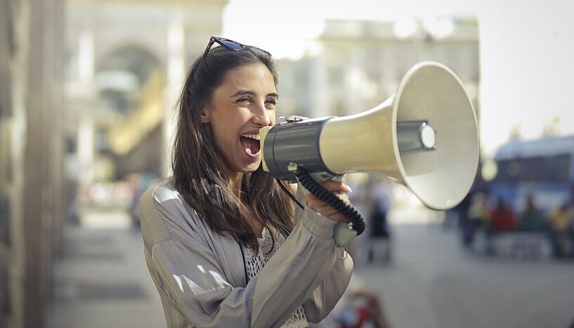 Woman standing on the street and speaking into a megaphone