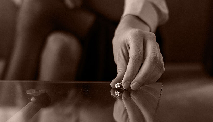 Symbolfoto: Frau legt Ehering auf den Tisch