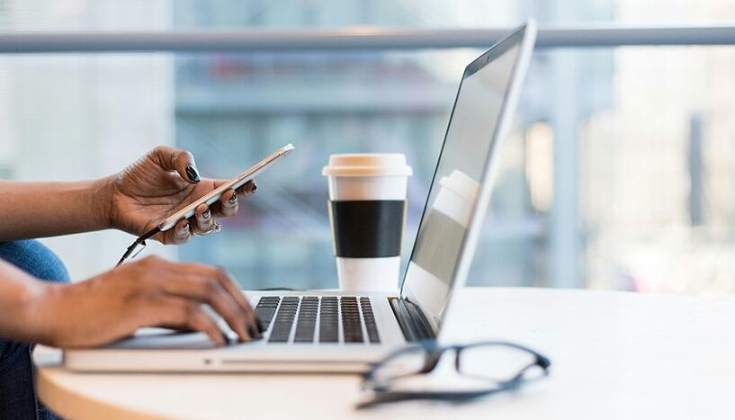 Ein Laptop steht auf einem Tisch, eine Person tippt darauf