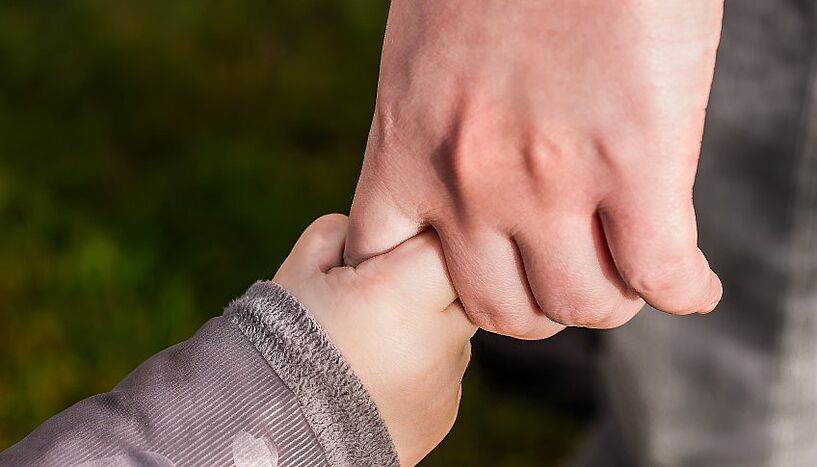 Die Hand eines Erwachsenen hält die Hand eines Kindes