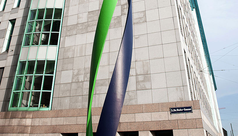 The facade of the Max F. Perutz Laboratories in Dr. Bohr-Gasse in the 3rd district. It is a beige-and-brown façade with a green-blue, sweeping artwork reminiscent of DNA.
