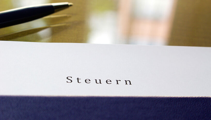 Das Symbolfoto zeigt einen Kugelschreiber auf einem Schreibtisch liegend.