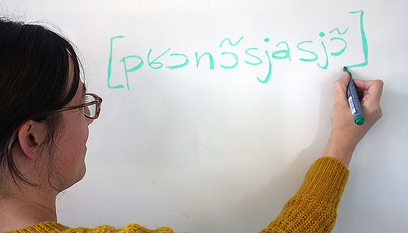 Elissa Pustka schreibt in Lautschrift auf eine Tafel.