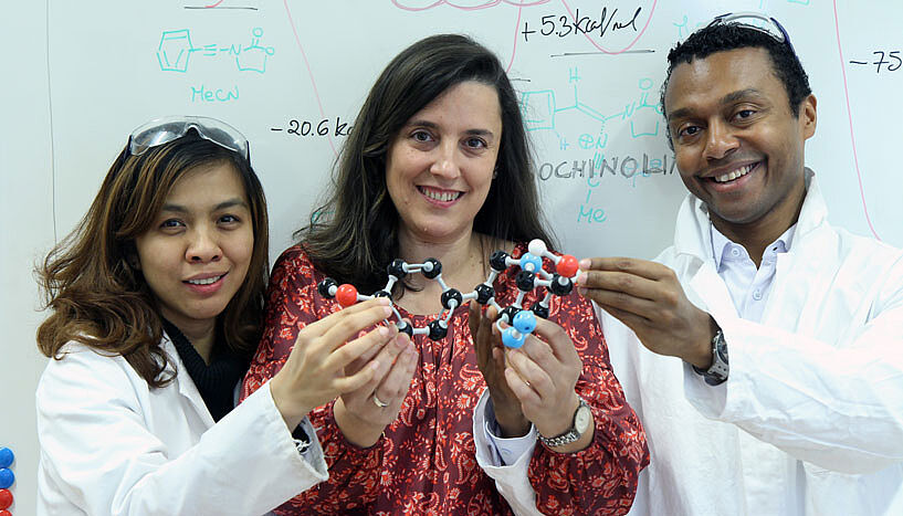 Supaporn Niyomchon, Leticia González und Nuno Maulide halten lächelnd ein Modell einer chemischen Verbindung.