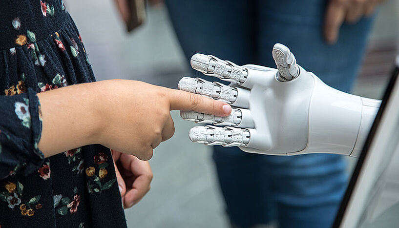 Mensch und Roboter geben sich die Hand