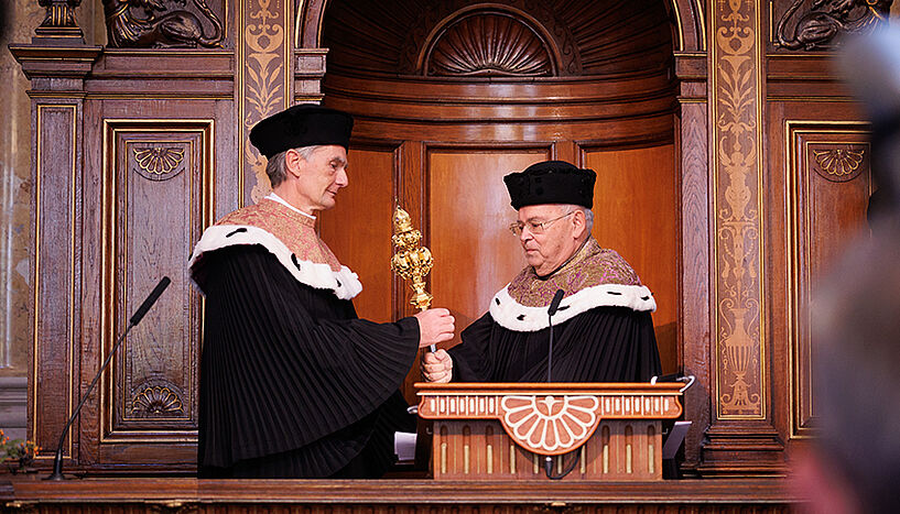 Heinz W. Engl solemnly passing over the Rector’s sceptre to Sebastian Schütze, the new Rector of the University of Vienna.